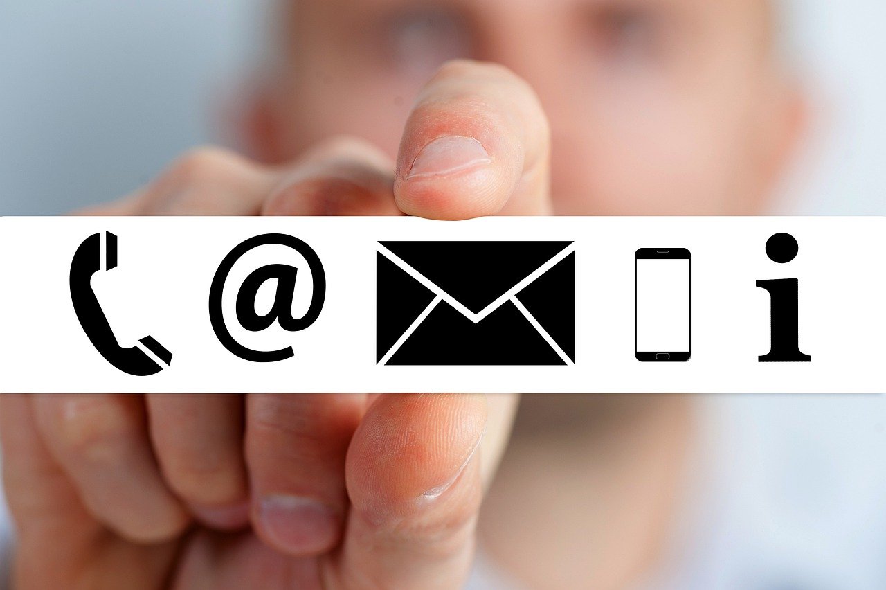 Eine Hand hält Symbole für Telefon, E-Mail, Brief, Handy und Information.